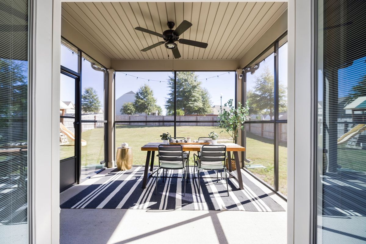 A screened patio with fly-screen panels between the posts and a dining table inside