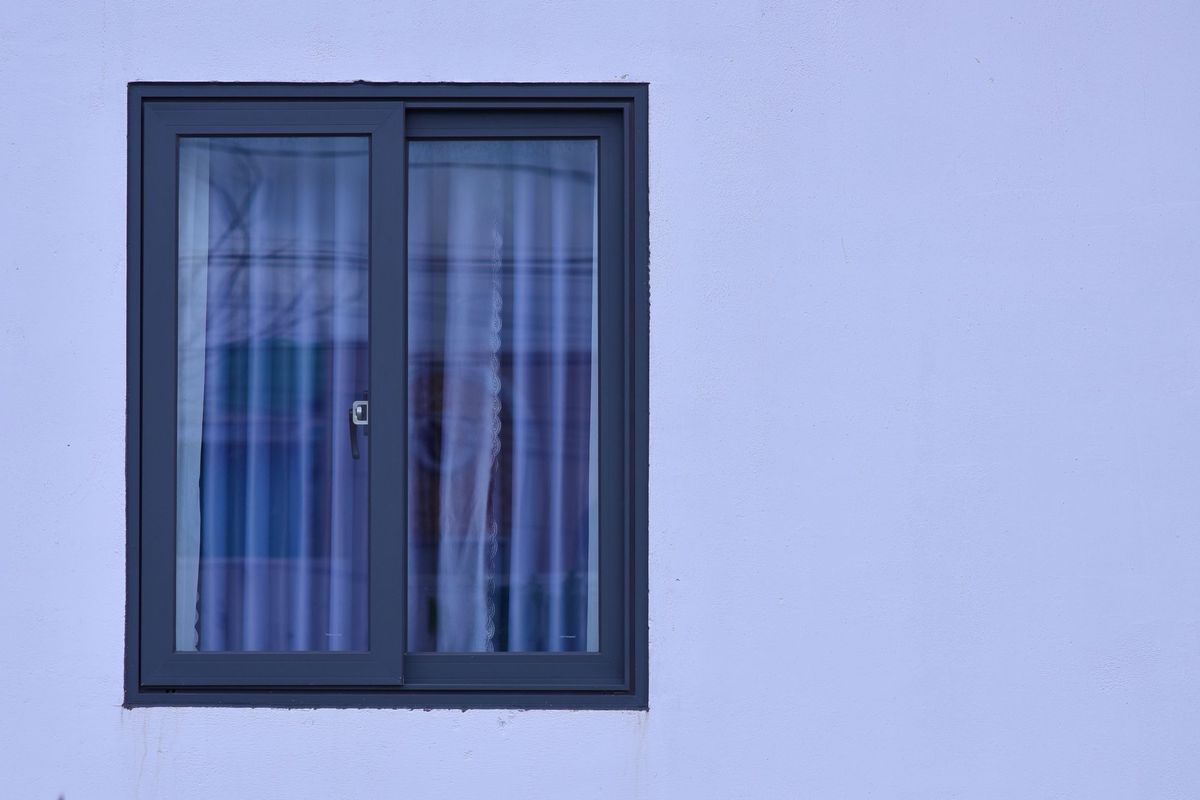 A dark-framed two-pane sliding window set in a pale wall